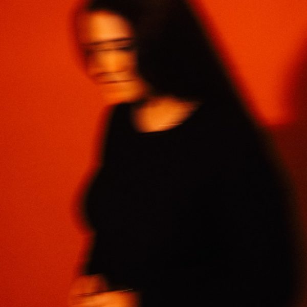 Blurred woman in black against red wall